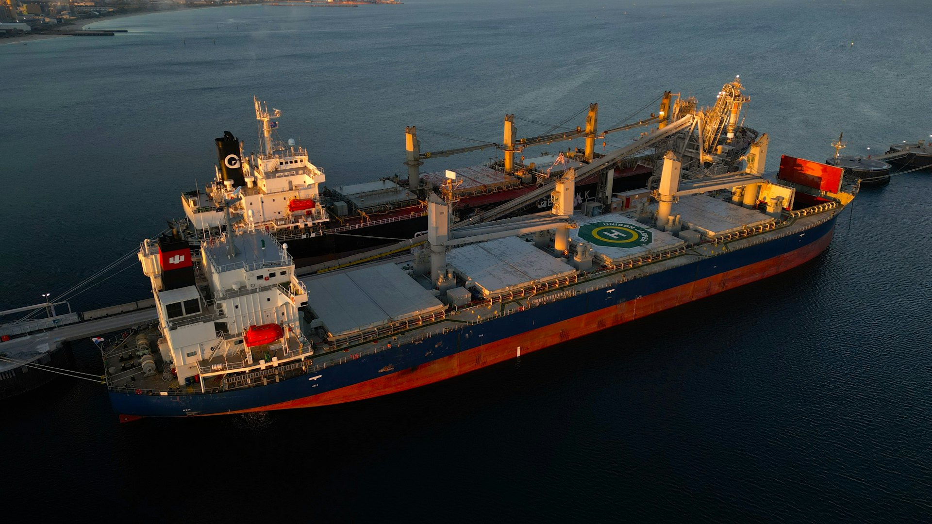 Large cargo ship berthed at a port at dusk